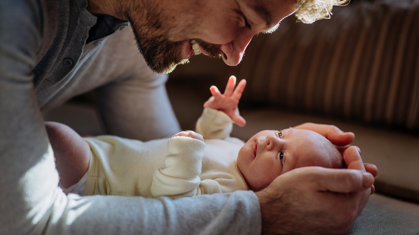 Un père tient tendrement son bébé dans ses mains et est heureux d’avoir une bonne assurance maladie pour son bébé.